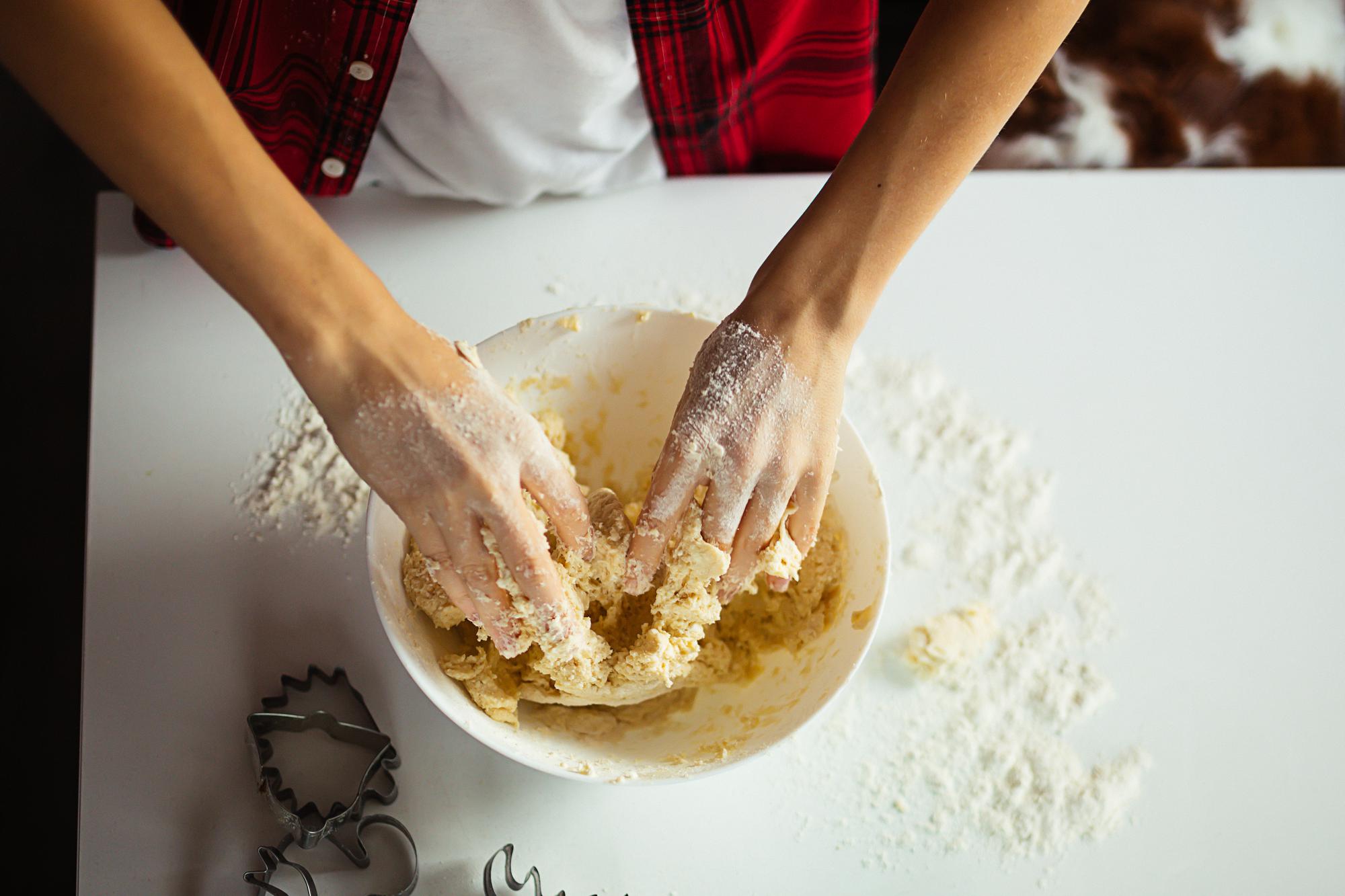 Hands kneading dough on a floured board