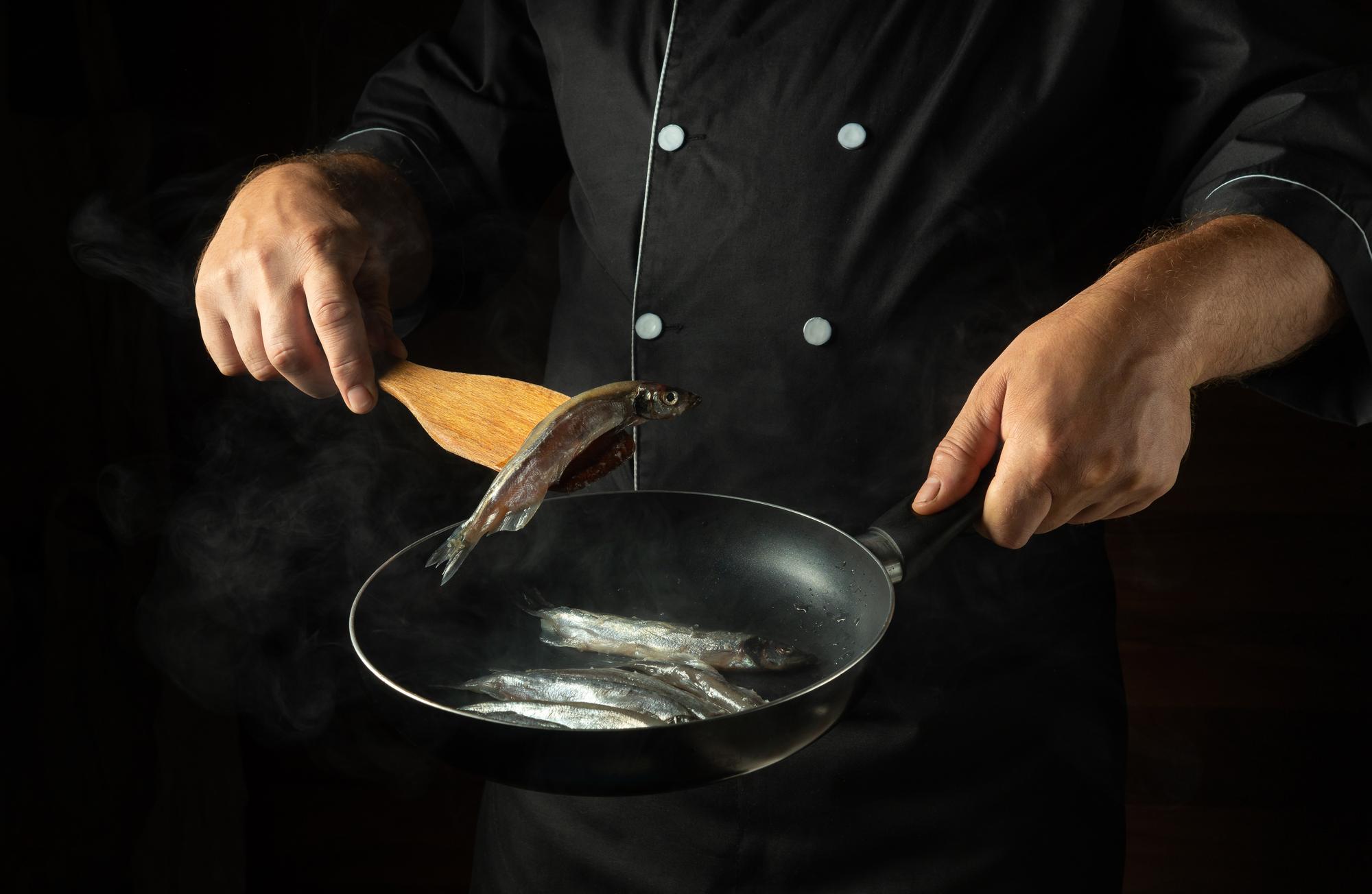 Chef searing fish on a hot pan