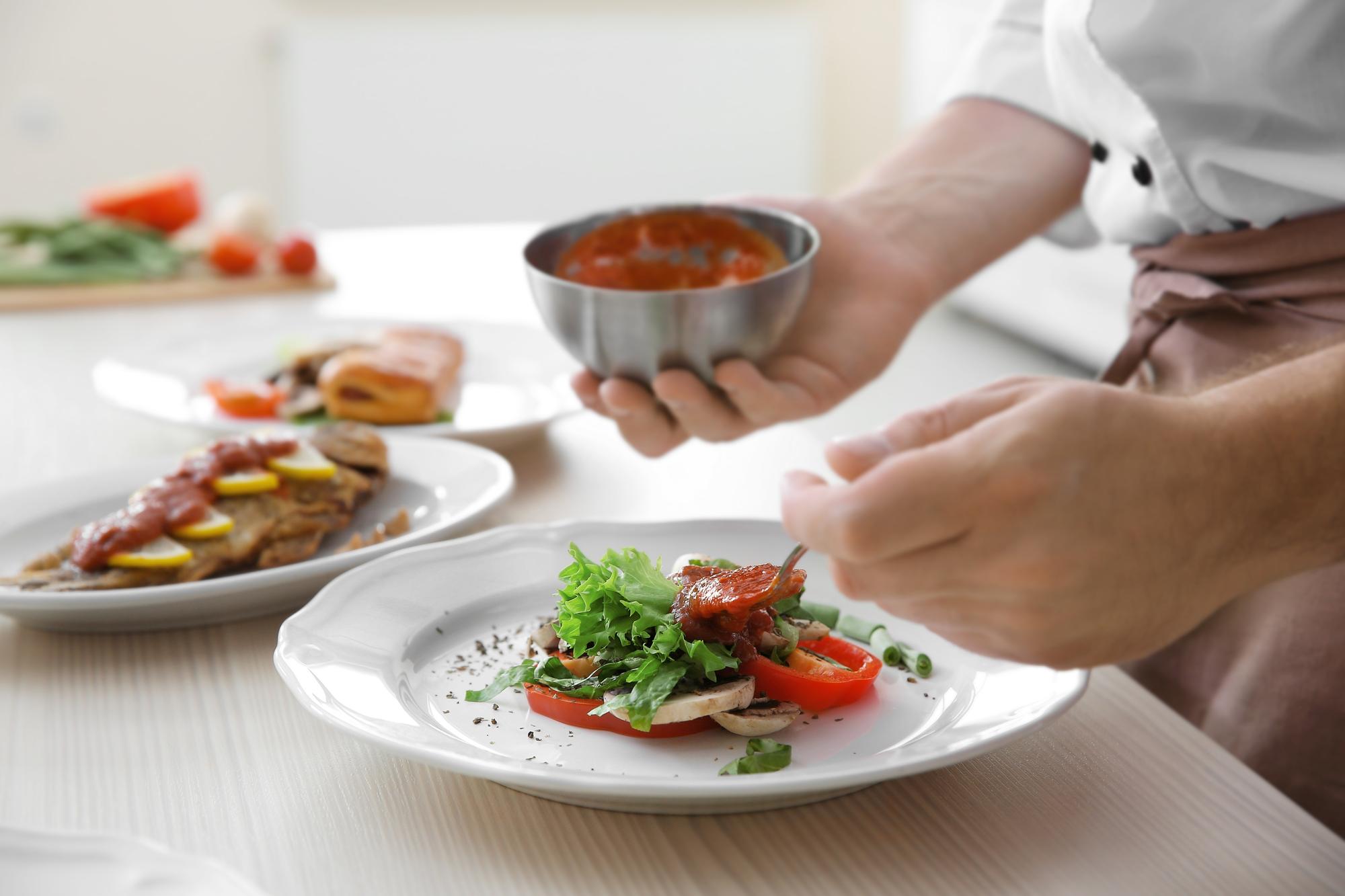 Chef plating a composed dish in natural light